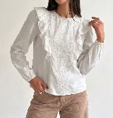 Blusa de color blanco con bordados florales en el frente y volados laterales. Posee escote redondo, mangas largas con puños elásticos y corte recto.