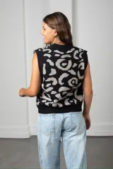 Chaleco de punto con diseño animal print en tonos gris y negro, con cuello en V y borde frontal en color rojo vibrante. Presenta cierre frontal con botones grandes y corte holgado.
