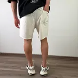 Short de algodón color beige melange, de diseño cómodo y holgado con bolsillos laterales y terminación descosida en las perneras.