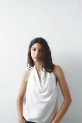 Top blanco de tejido satinado con cuello halter drapeado ajustable con lazada en el cuello y espalda descubierta con lazada.