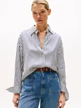 Camisa oversize de manga larga con cuello clásico y puños abotonados. Diseño a rayas verticales en blanco y azul marino.