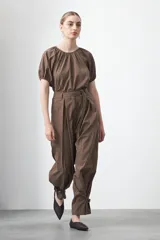 Pantalón baggy negro de silueta relajada con volumen amplio y caída fluida. Presenta detalles de ajuste con hebillas metálicas en el bajo y un cinturón de tela con hebilla metálica en la cintura.