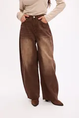 Pantalón de jean estilo baggy, de corte amplio y tiro medio, confeccionado en denim negro con textura de pana fina. Presenta diseño de cinco bolsillos, cierre frontal con botón metálico y cremallera, y perneras holgadas.