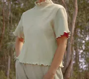 Remera de punto color verde claro, con cuello alto y mangas cortas con terminación ondulada.