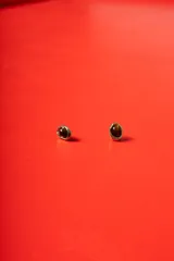 Aros tipo caravanas con diseño orgánico de bordes irregulares en tono dorado, con centro de piedra pulida en color marrón oscuro.