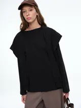 Buzo negro de algodón con diseño de efecto superpuesto, que simula una prenda atada sobre los hombros. Presenta cuello redondo, mangas largas con puños ajustados y un corte holgado.
