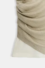 Top sin mangas color beige claro, con cuello redondo y efecto doble capa, donde la capa superior presenta un drapeado fruncido en el lateral izquierdo.