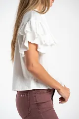 Blusa blanca de algodón con cuello mao, cierre frontal de botones y volados en los hombros con detalle de bordado inglés.