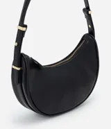 Bolso baguette en formato media luna, con correa de hombro ajustable mediante detalles metálicos y cierre superior por cremallera. Diseño minimalista con acabado liso.