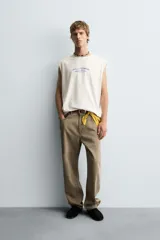 Camiseta tipo tank (sin mangas) de corte relajado, color blanco roto con efecto lavado. Presenta un estampado frontal en azul con texto en francés: "Coquillages Grillés De Côte-Marine" y "Salty Shack".