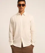 Camisa de manga larga color crema, con cuello inglés, abotonada y textura de rayas verticales.