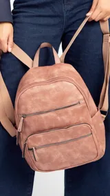 Mochila color marrón claro de símil cuero con bolsillos frontales con cierre. Tiene asa de mano rígida y correas regulables.