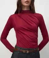 Body de manga larga confeccionado en poliamida y elastano, con cuello alto y diseño con fruncidos en hombros y laterales. Prenda versátil de calce ajustado.