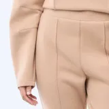 Pantalón de felpa ligera en color beige, con corte bootcut y costura central vertical en el frente de cada pierna.