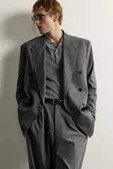 Blazer gris de corte relaxed fit con diseño de raya diplomática, cuello con solapas de pico, doble botonadura cruzada y bolsillos con solapa en la cadera.
