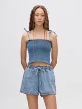 Short de denim color tostado, de corte relajado con cintura elástica y cordón ajustable. Posee un bolsillo trasero con un pequeño bordado de sol.