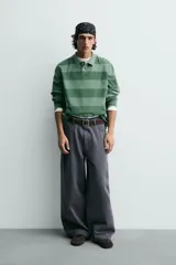 Pantalón wide fit color gris oscuro, confeccionado en tejido ligero de algodón. Cuenta con cinco bolsillos y efecto lavado. Cierre frontal con cremallera y botón.