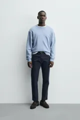 Pantalón chino de corte ajustado, color beige, con bolsillos laterales y bolsillos traseros de vivo. Cuenta con cierre frontal de cremallera y botón.