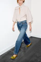 Jeans de tiro alto con corte culotte y pernera ancha. Presenta bolsillos de plastrón en el frente con detalle de pespuntes decorativos en forma de onda y costuras verticales a lo largo de la pierna. Cierre frontal con cremallera y botón metálico.