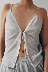 Top de punto elástico color gris, con escote en V, tirantes finos, aplicación de puntilla a contraste y cierre frontal con lazada.