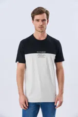 Remera de algodón y poliéster de corte clásico, con diseño en bloques de color negro en la parte superior y gris melange en la inferior. Presenta cuello redondo, mangas cortas y un pequeño estampado tipográfico en el pecho.