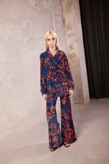Camisa de terciopelo azul con estampado barroco en color naranja, de corte recto, cuello clásico y cierre frontal con botones.