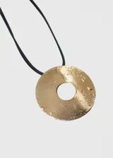 Collar con doble tira de cuerina negra y dije circular dorado con textura irregular.