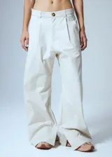 Pantalón sastrero de gabardina color beige, con pinzas delanteras, presillas anchas en la cintura y tajo interno en la botamanga.
