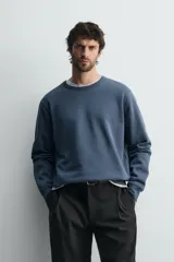Sudadera de corte regular fit, color gris melange, con cuello redondo, manga larga y acabados en rib. Confeccionada en tejido de algodón con interior afelpado.
