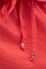 Falda larga color coral, estilo cargo, con cintura regulable con cordón, tajo frontal y bolsillos laterales con solapa.