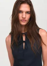 Top sin mangas con cuello redondo y detalle de lazos frontales. Presenta un diseño entallado con efecto denim.
