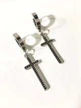 Par de aros colgantes plateados con forma de cruz y detalles de pequeñas piedras negras.