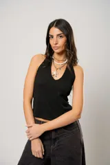 Top negro con escote halter y espalda semi descubierta, confeccionado en tejido con textura sutil. Presenta un diseño ajustado al cuerpo y logo bordado en la parte inferior de la espalda.