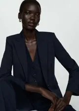 Blazer entallado de color azul marino con cuello de solapa con muesca, hombros estructurados y cierre frontal de un botón. Presenta diseño recto con pinzas, dos bolsillos de ribete delanteros y abertura posterior.