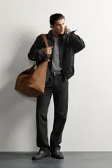 Jeans slim straight fit para hombre, confeccionados en denim de algodón negro sin lavados. Presentan diseño de tiro bajo, pierna recta y cinco bolsillos, con cierre frontal de botonadura.
