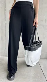 Pantalón negro de lino, de corte ancho y largo, con diseño suelto y botones decorativos en la cintura.