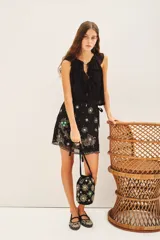 Falda corta cruzada con diseño envolvente y lazo lateral para ajuste. Presenta bordados florales detallados en toda la superficie, tanto en el frente como en la espalda. Está completamente forrada para mayor comodidad.