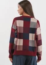 Sweater de punto con diseño de cuadros grandes en tonos bordó, marrón y beige. Presenta cuello redondo y terminaciones acanaladas en puños y cintura.