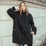 Tapado de textura tipo corderito en color negro, con diseño de paneles combinados en tela lisa, cierre frontal y cuello alto. Presenta un corte recto y largo, ideal para climas fríos.