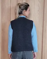 Chaleco de punto con diseño de trenzas, color gris oscuro, con cierre frontal de botones grandes y bolsillos laterales.