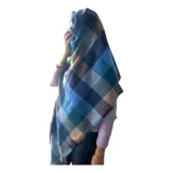 Bufanda rectangular de tejido afelpado con diseño de cuadros en tonos rosado, gris y beige. Presenta terminaciones con flecos en los extremos.