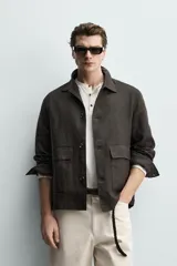 Sobrecamisa relaxed fit confeccionada en tejido de lino de color negro, con cuello solapa, manga larga con puño abotonado, bolsillos de plastrón en la cadera y cierre frontal de botones.