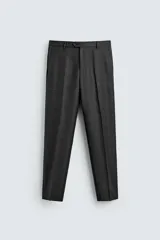 Pantalón de traje de corte regular fit confeccionado en lana de origen italiano. Presenta un diseño de cuadros sutiles, bolsillos laterales, bolsillos traseros de doble vivo con botón y cierre frontal con cremallera y botón.