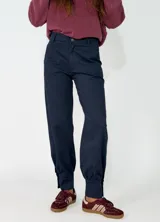 Pantalon de gabardina en color azul oscuro, de corte holgado con botamangas ajustadas mediante elástico.