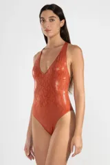 Malla enteriza color ladrillo con estampado de piel de serpiente, escote en V y espalda descubierta con tiras cruzadas unidas por un detalle metálico cuadrado.