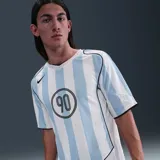 Camiseta de fútbol Nike Total 90 con diseño de rayas verticales celestes y blancas. Presenta cuello en V, mangas cortas y el logo circular T90 impreso en el centro del pecho junto con el swoosh de Nike en el lateral superior derecho.