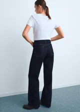 Jeans Danila de corte wide leg, tiro alto y color azul oscuro, con diseño clásico de cinco bolsillos, trabillas para cinto y cierre frontal con cremallera y botón.