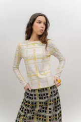 Remera de manga larga de algodón elastizado, con cuello redondo y estampado geométrico floral en tonos blanco, amarillo, verde y rosado.