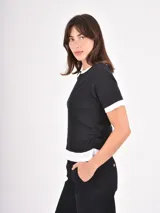 Remera de algodón en color negro con detalles en blanco en el cuello, mangas y ruedo. Presenta un diseño de estilo ringer con terminaciones acanaladas.