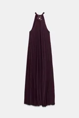 Vestido midi plisado color bordó, con cuello halter, broche de flor en el delantero y anudado en la espalda. Cuenta con forro interior.